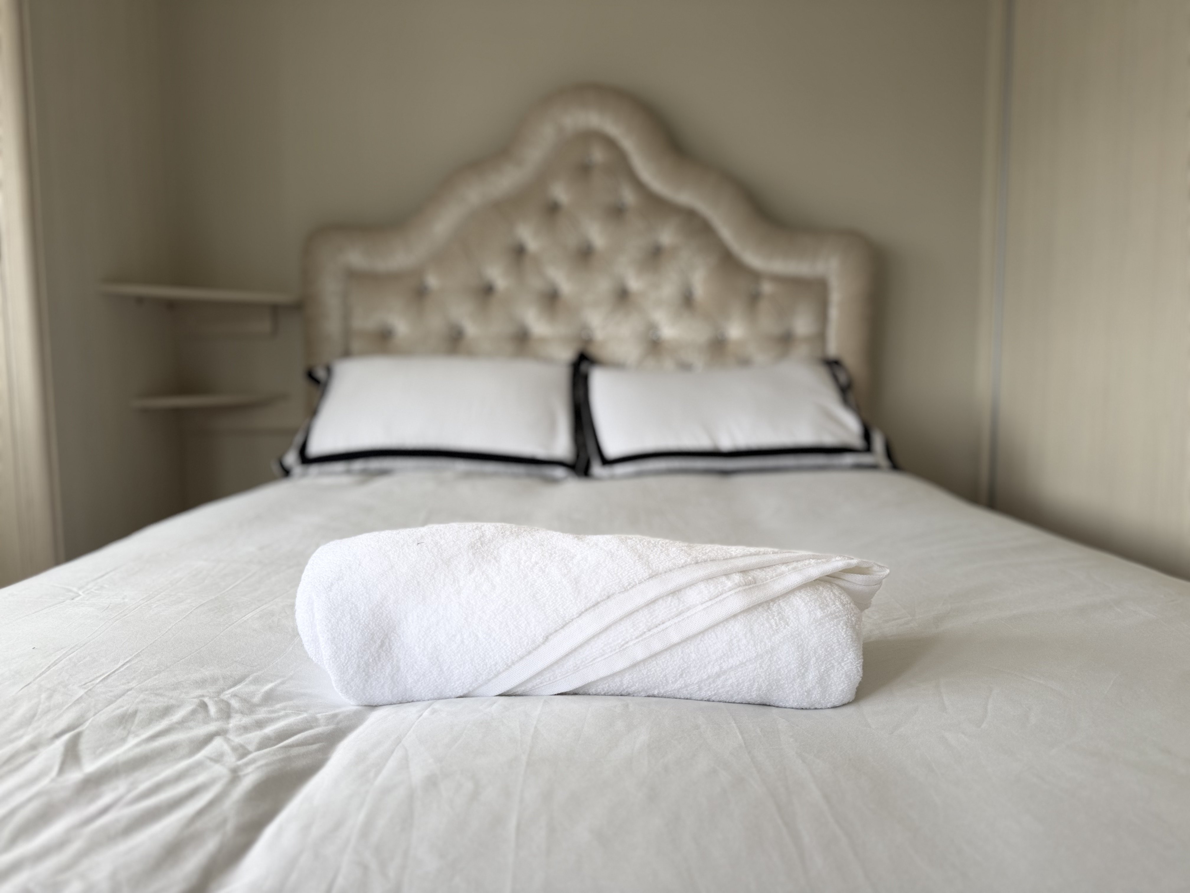 Borkwood Way master bedroom with buttoned headboard and fresh towels