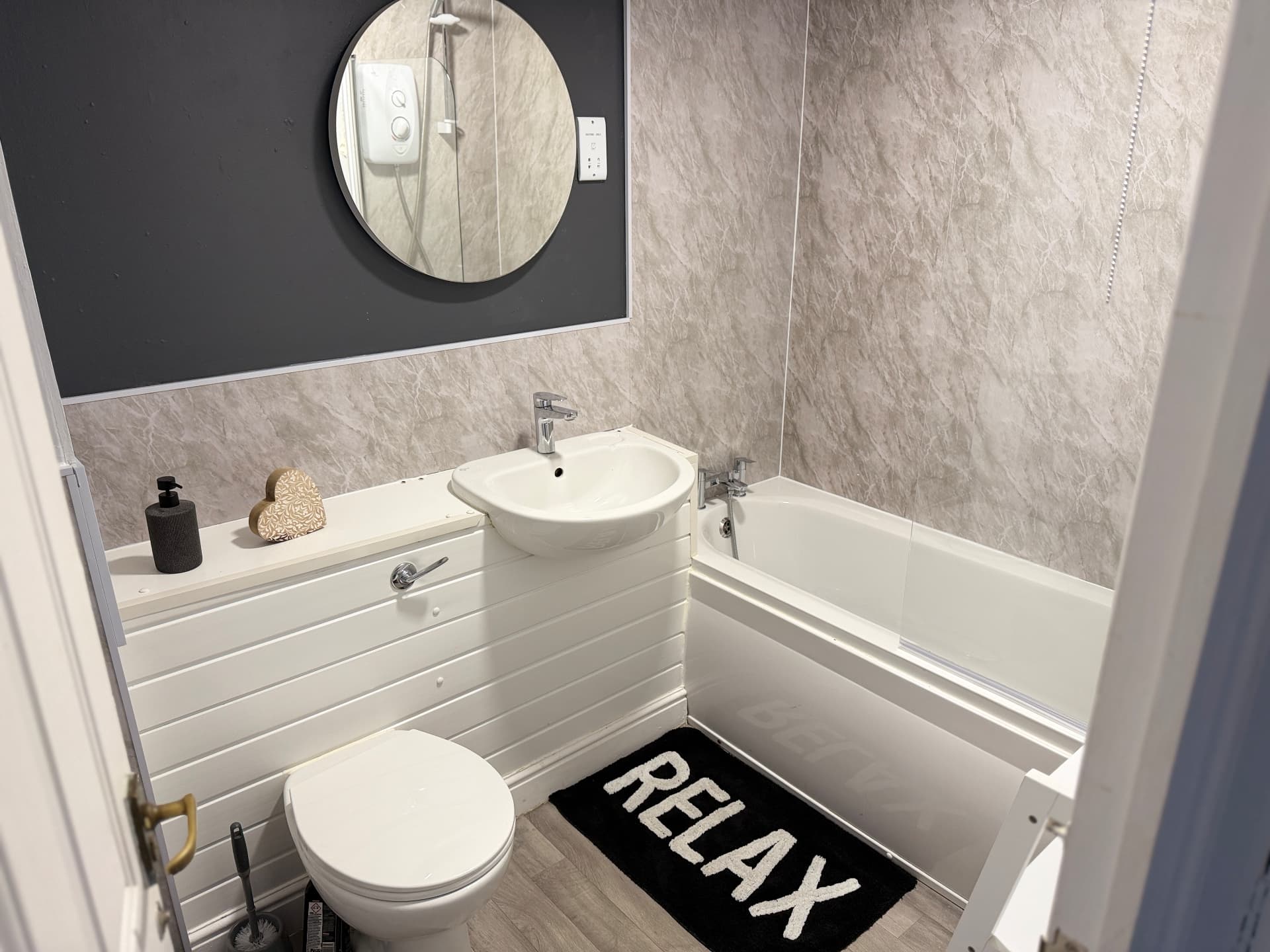 Century House bathroom with toilet, vanity basin, bath, shower and round mirror